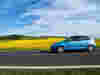 A blue car driving down a country road